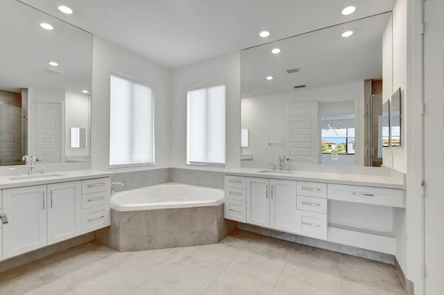 bathroom with tile patterned flooring, tiled tub, and vanity