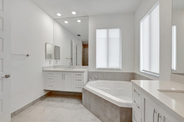 bathroom featuring vanity, tiled tub, and tile patterned flooring