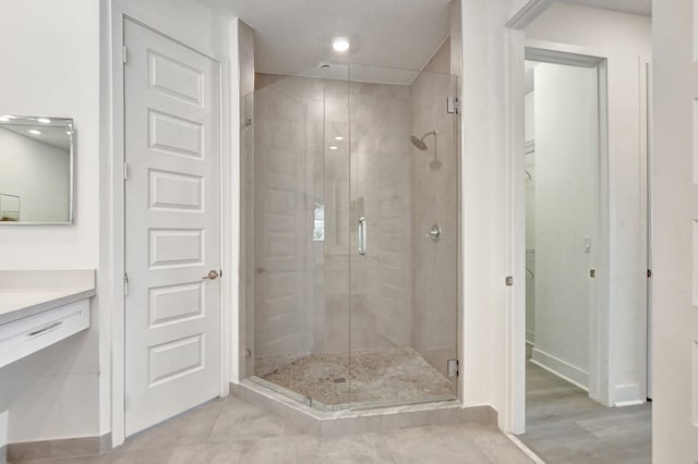 bathroom with tile patterned floors, a shower with door, and vanity