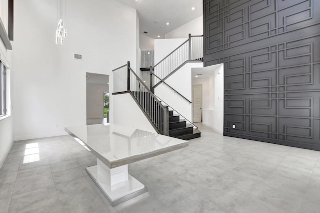 stairway with light tile patterned floors and a high ceiling