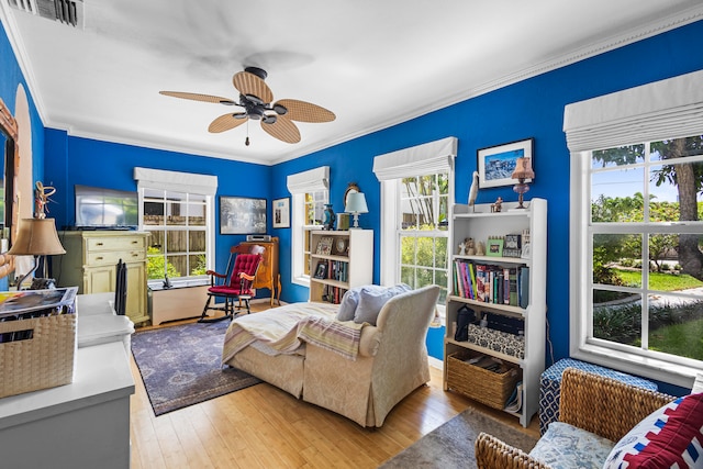 living room featuring wood-type flooring, ceiling fan, and crown molding