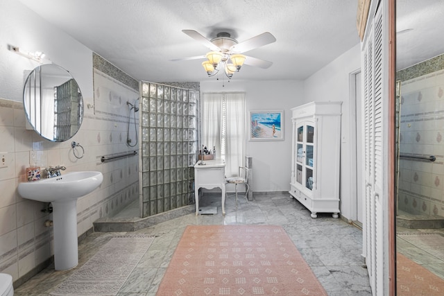 bathroom with a textured ceiling, ceiling fan, tile walls, and tile patterned flooring