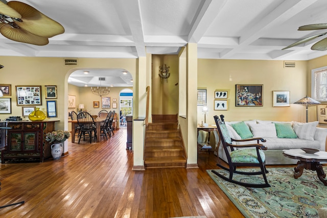 living room featuring coffered ceiling, beam ceiling, ceiling fan with notable chandelier, and hardwood / wood-style floors