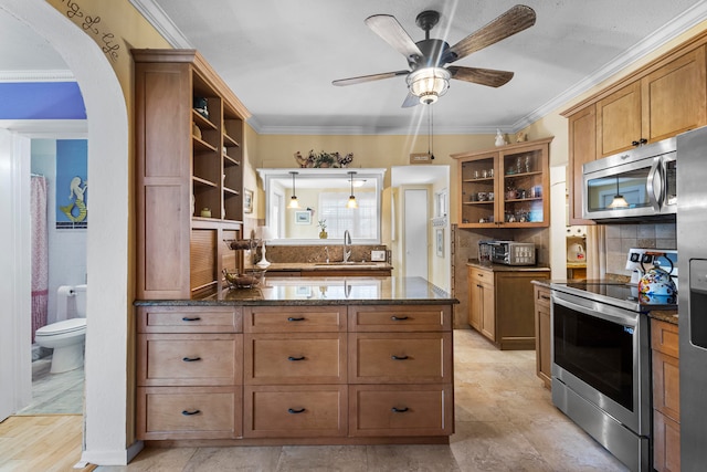 kitchen with ceiling fan, stainless steel appliances, sink, dark stone countertops, and light tile patterned floors