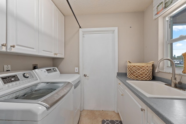 laundry area with sink, light tile patterned floors, cabinets, a textured ceiling, and washing machine and clothes dryer