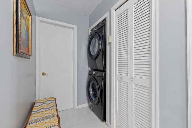 clothes washing area with stacked washer / drying machine and light tile patterned floors