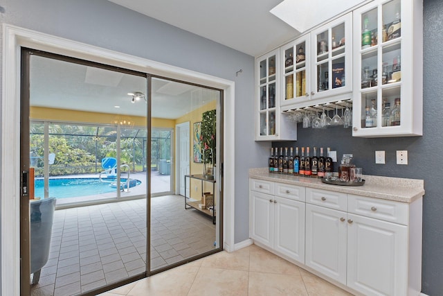 bar featuring light stone counters, light tile patterned floors, and white cabinets