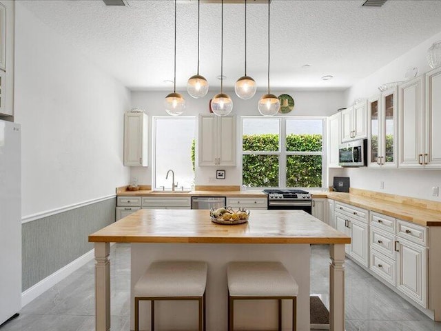 kitchen with a kitchen bar, butcher block counters, sink, a center island, and stainless steel appliances