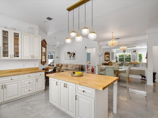 kitchen featuring white cabinetry, wood counters, a center island, and vaulted ceiling