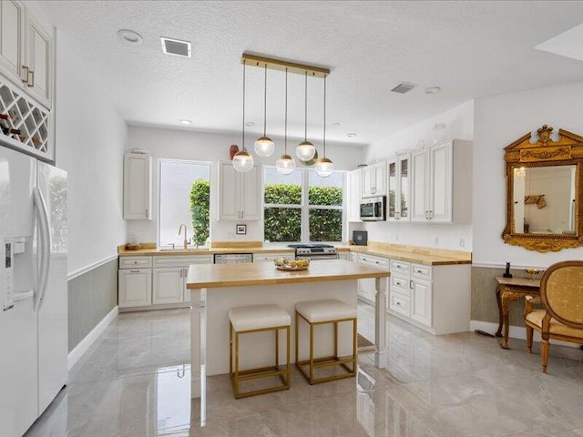 kitchen featuring white cabinetry, light tile patterned flooring, a textured ceiling, and stainless steel appliances