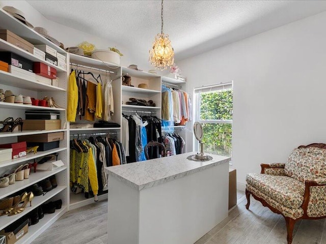 walk in closet featuring light hardwood / wood-style flooring and an inviting chandelier