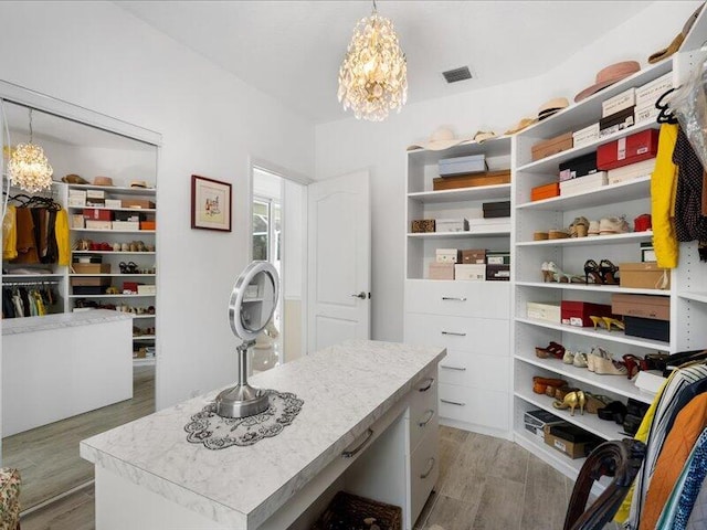 spacious closet with a notable chandelier and light hardwood / wood-style floors