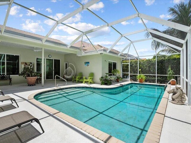 view of swimming pool featuring ceiling fan, a patio area, and a lanai