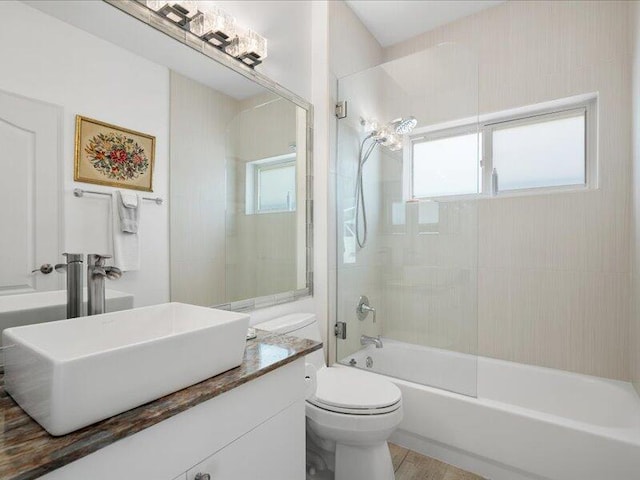 full bathroom with a wealth of natural light, vanity, tiled shower / bath, and toilet