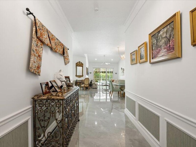 corridor with ornamental molding, light tile patterned floors, and a textured ceiling