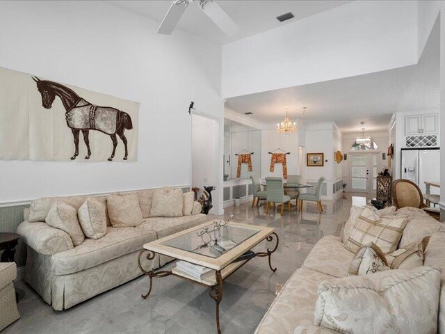 tiled living room with ceiling fan with notable chandelier