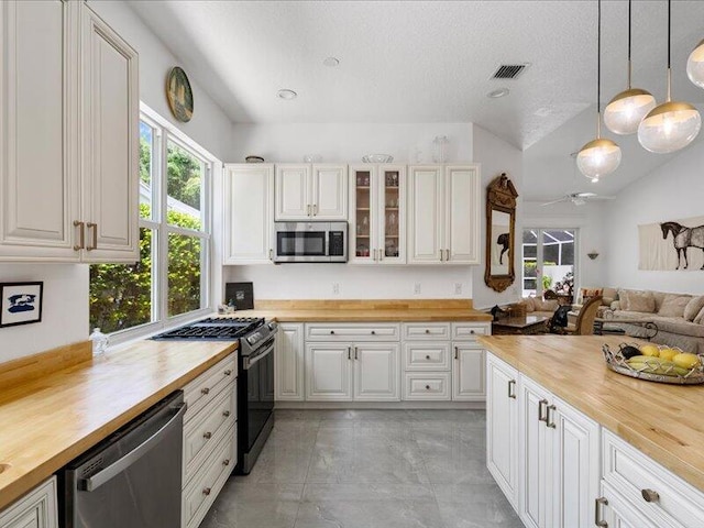 kitchen with pendant lighting, appliances with stainless steel finishes, butcher block counters, and white cabinets