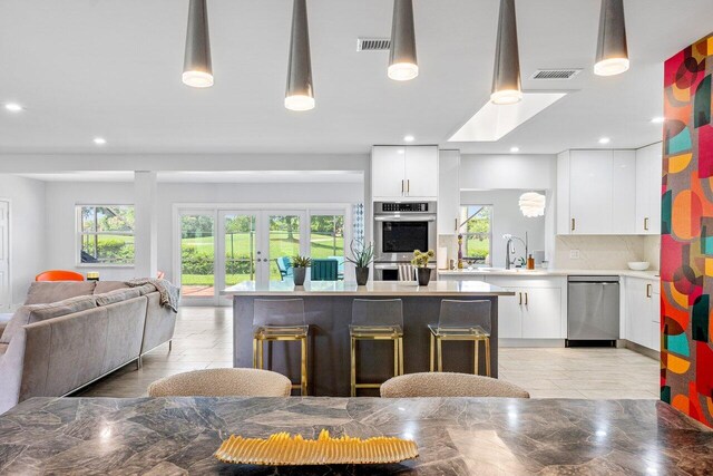 kitchen with light tile patterned flooring, white cabinets, backsplash, appliances with stainless steel finishes, and sink