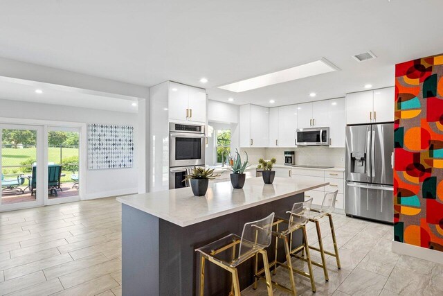 kitchen with decorative backsplash, appliances with stainless steel finishes, a center island, and white cabinetry