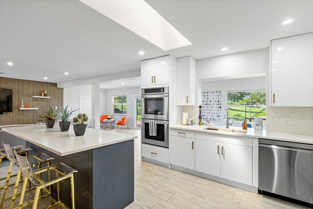 kitchen with white cabinetry, decorative backsplash, sink, a breakfast bar, and appliances with stainless steel finishes