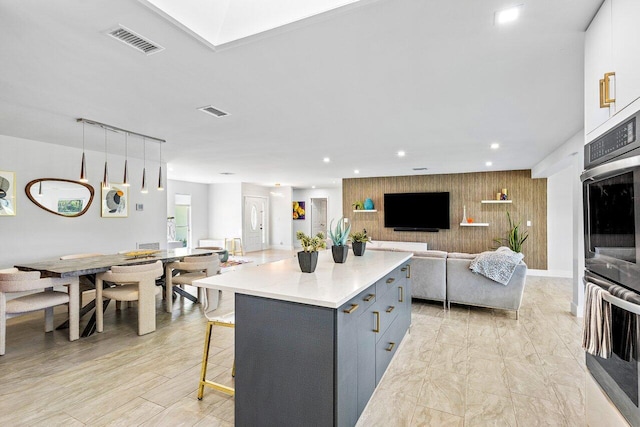 kitchen with a breakfast bar area, white cabinets, a center island, gray cabinets, and pendant lighting