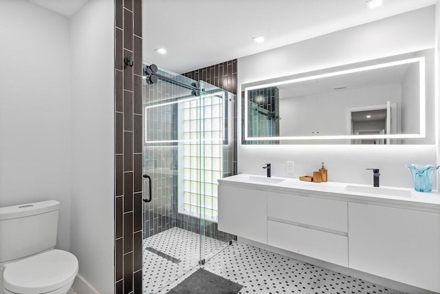 bathroom featuring a shower with door, double sink vanity, and toilet