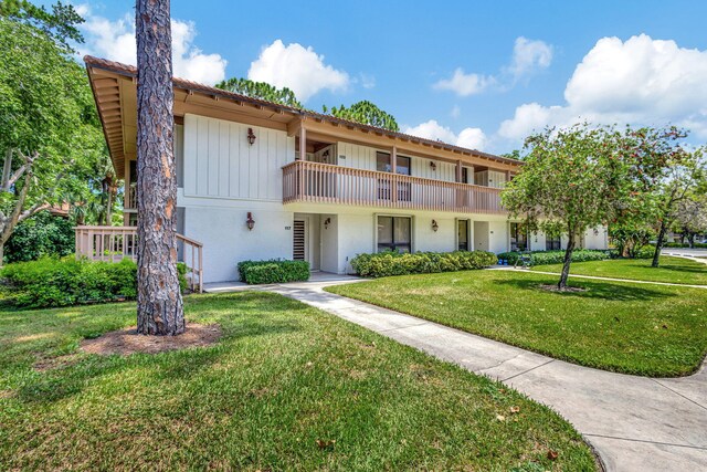 view of front of house with a balcony and a front yard