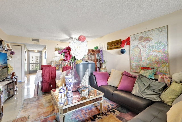 living room with tile patterned flooring, ceiling fan, and a textured ceiling