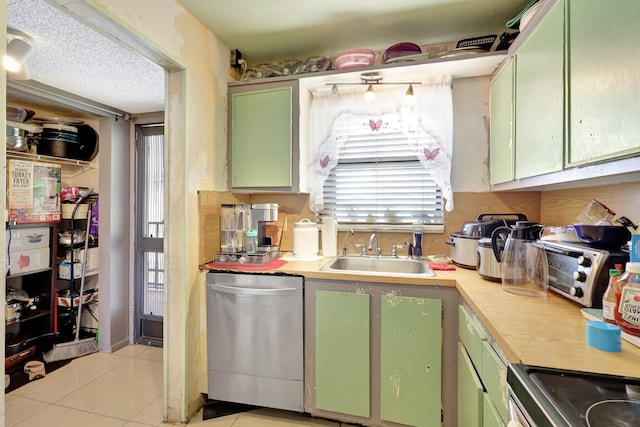 kitchen featuring sink, dishwasher, green cabinetry, and light tile patterned floors