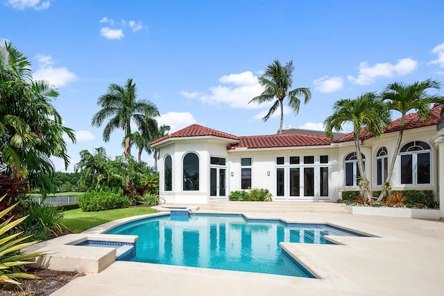 rear view of property with a patio and a pool with hot tub