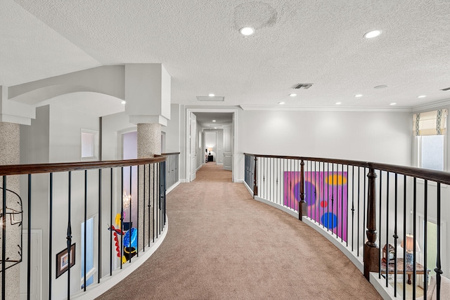 hallway with crown molding, a textured ceiling, and light colored carpet