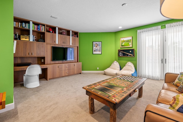 living room with light carpet, a textured ceiling, and built in desk