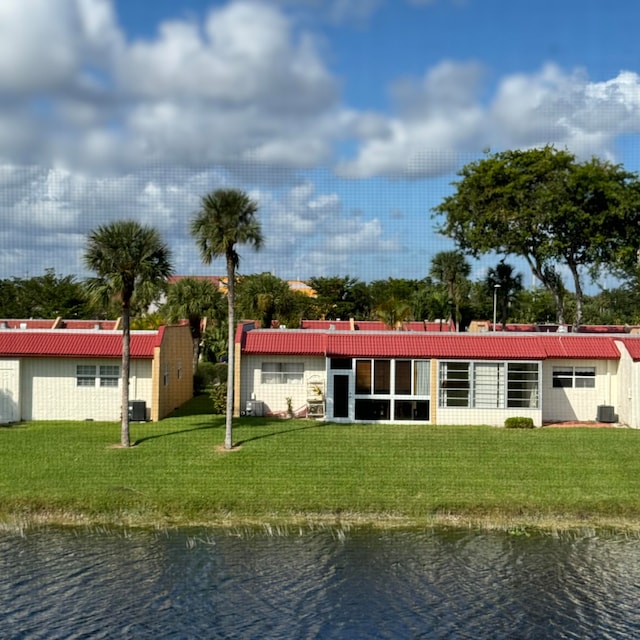 back of house featuring a water view, central AC unit, and a lawn