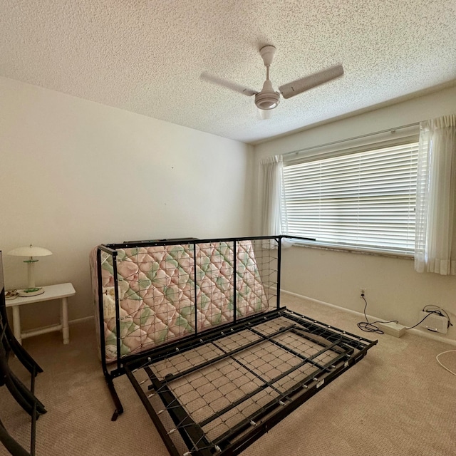 bedroom featuring ceiling fan, carpet floors, and a textured ceiling