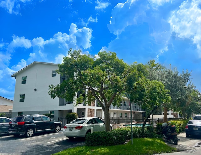 view of building exterior featuring uncovered parking and fence