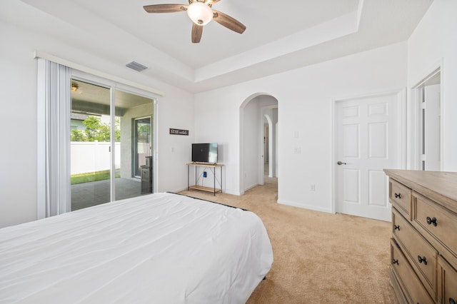 carpeted bedroom featuring ceiling fan, a raised ceiling, and access to outside