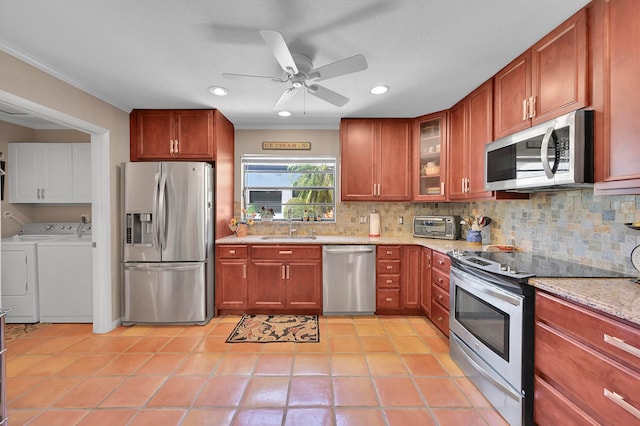 kitchen featuring appliances with stainless steel finishes, light tile patterned floors, light stone countertops, separate washer and dryer, and ceiling fan