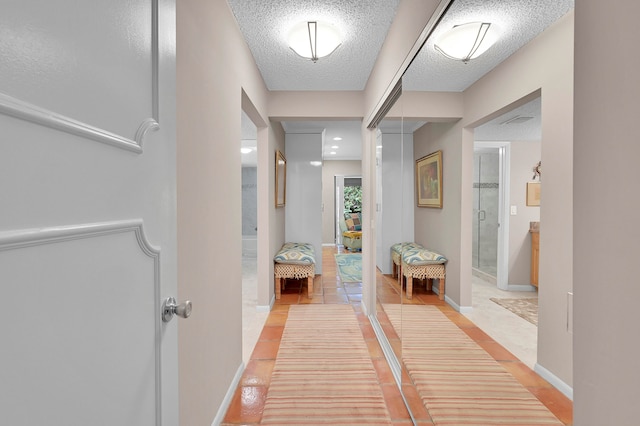 corridor with a textured ceiling and light tile patterned floors