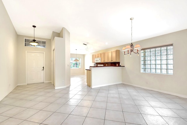 interior space with an inviting chandelier, light tile patterned floors, hanging light fixtures, and light brown cabinets