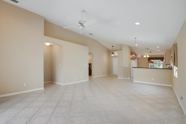 tiled spare room featuring lofted ceiling and ceiling fan with notable chandelier