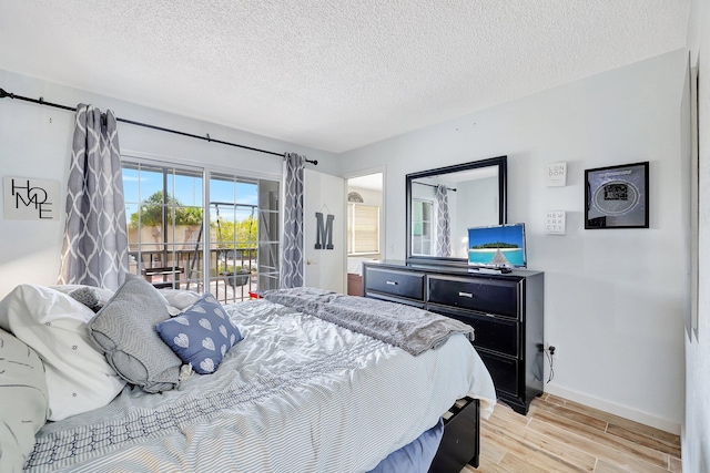 bedroom with access to exterior, light hardwood / wood-style flooring, and a textured ceiling