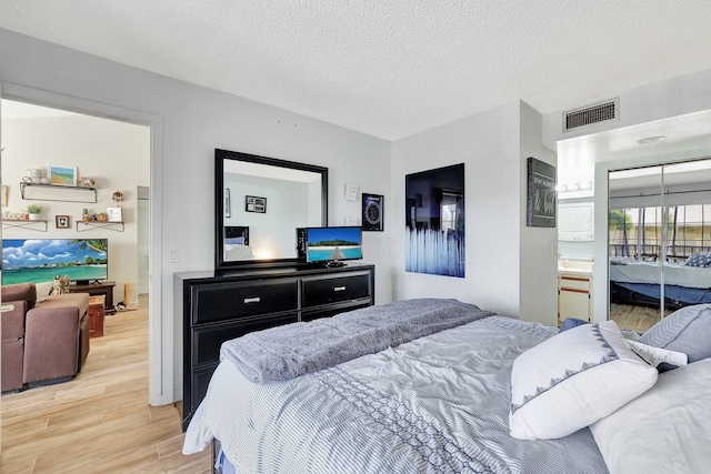 bedroom with a textured ceiling and light hardwood / wood-style flooring