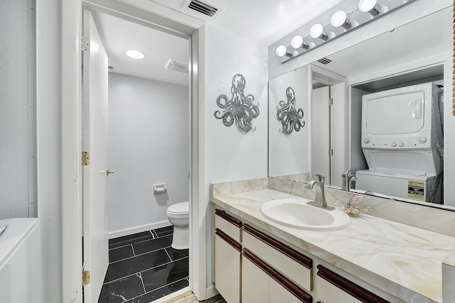 bathroom featuring tile patterned flooring, vanity, stacked washer and clothes dryer, and toilet