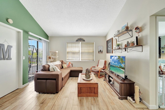 living room with lofted ceiling, light hardwood / wood-style floors, and a textured ceiling