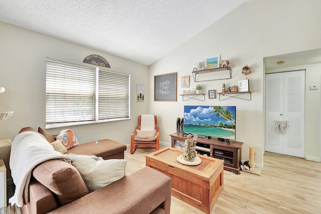 living room with vaulted ceiling, a textured ceiling, and light wood-type flooring