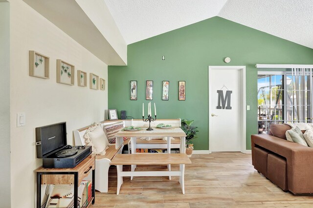 interior space featuring a textured ceiling, lofted ceiling, and light wood-type flooring