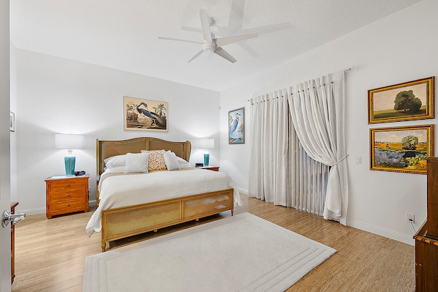 bedroom with light hardwood / wood-style flooring, a textured ceiling, and ceiling fan