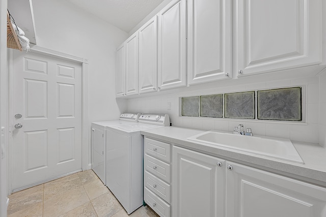 washroom featuring a textured ceiling, cabinets, sink, and washing machine and clothes dryer