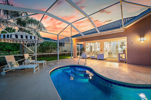 pool at dusk featuring a patio area and glass enclosure