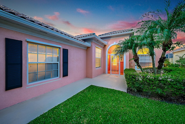 exterior entry at dusk featuring a yard